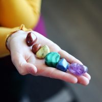 pierres roulées marron, jaune,vert, bleu et violet dans la main d'une femme